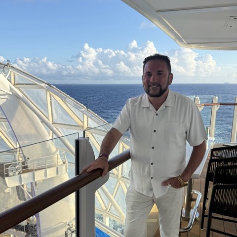 Hank smiling on an upper deck with the open ocean behind him